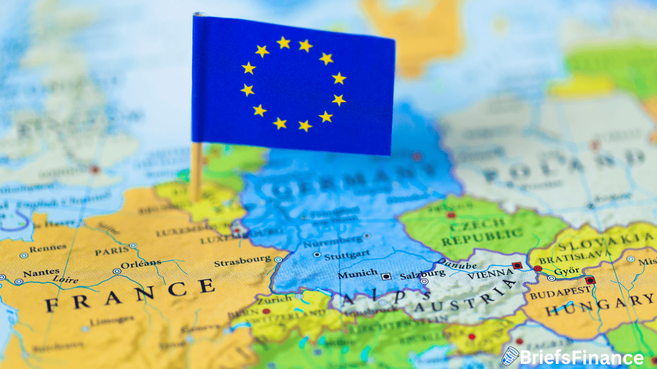 A small European Union flag is pinned on a map, marking a location in central Europe near Germany, France, and surrounding countries.