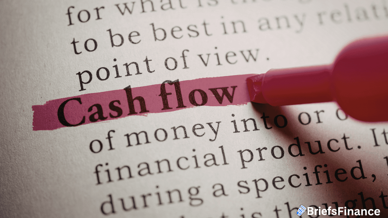 The term "Cash flow" is highlighted in pink on a printed dictionary page, with the tip of a pink highlighter visible.