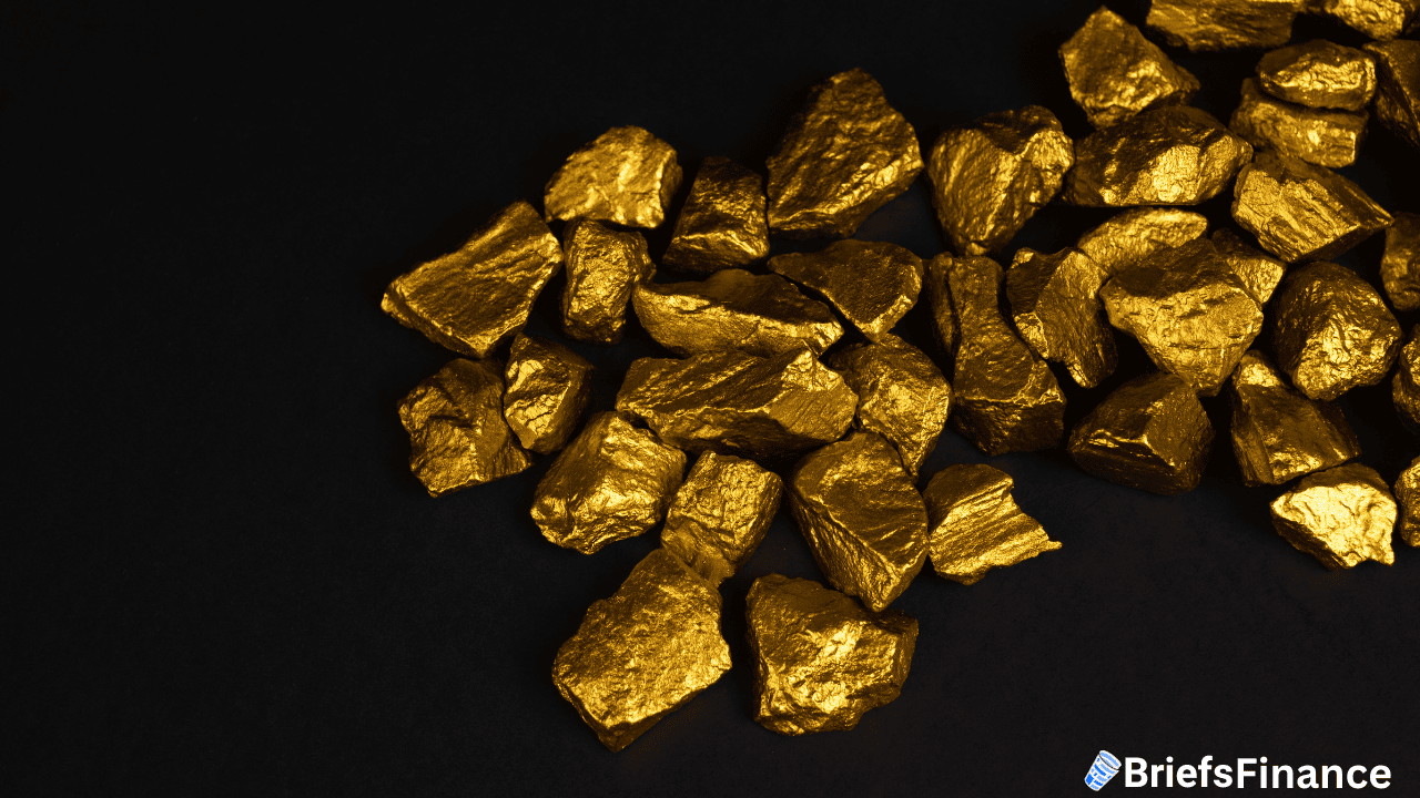 A pile of gold nuggets on a black surface, with a "BriefsFinance" logo in the bottom right corner.
