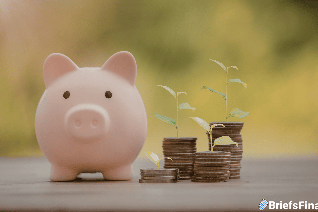 A pink piggy bank beside stacks of coins with small green plants growing on top, symbolizing financial growth and saving.