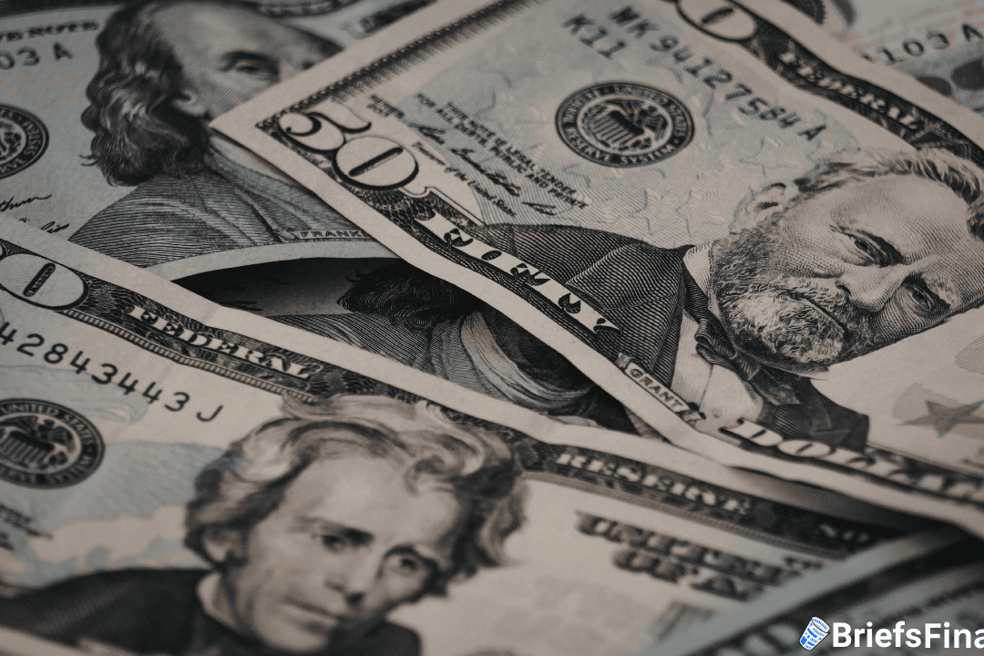 Close-up of overlapping U.S. paper currency, including $50, $20, and $100 bills, displaying portraits of prominent historical figures.